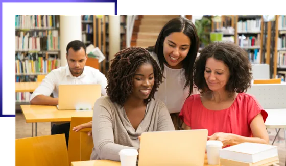 Equipe de uma organização reunida ao redor de uma mesa, trabalhando em notebooks