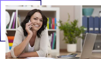 Gestora ao telefone em uma mesa de trabalho, com notebook e calculadora